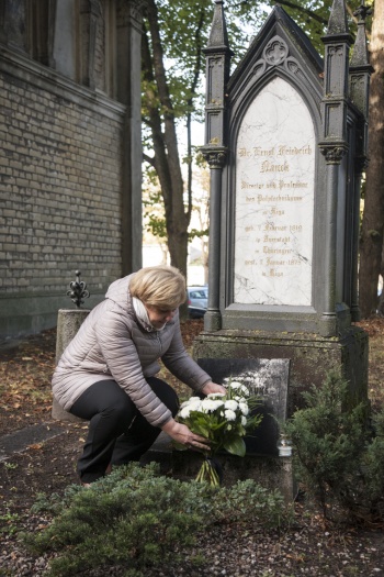 Profesore Elīna Gaile-Sarkane noliek ziedus pie E. Nauka kapa vietas.